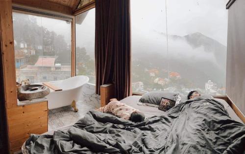 een man in bed in een kamer met een groot raam bij mimosa villa tam dao in Tam Ðảo