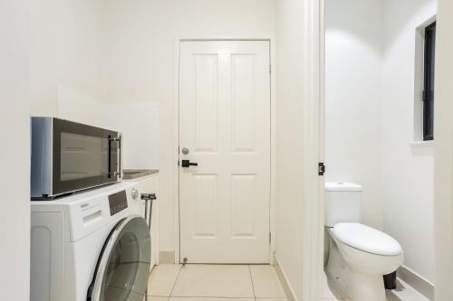 a white bathroom with a toilet and a tv at Nature View Southside Apartment in Cairns
