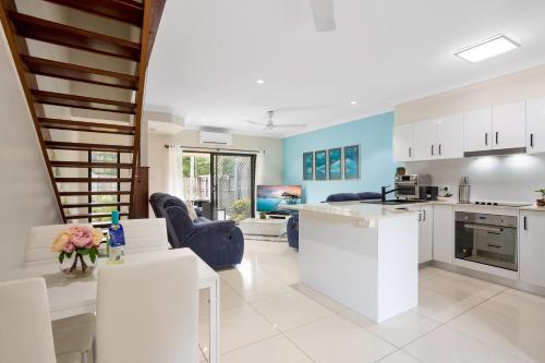 a kitchen and living room with white cabinets at Nature View Southside Apartment in Cairns