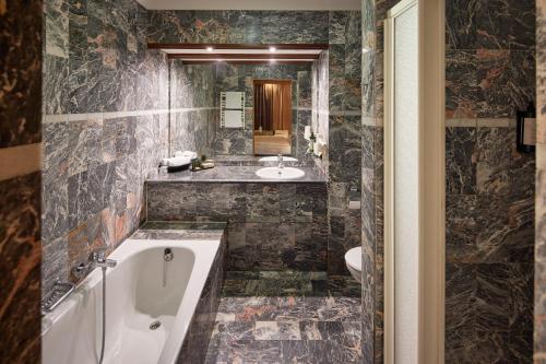 ein Badezimmer mit einer Badewanne und einem Waschbecken in der Unterkunft Hotel Gladbeck van der Valk in Gladbeck