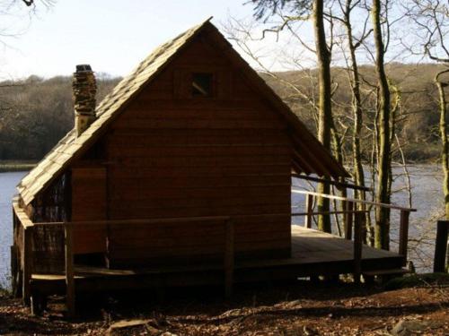 a small wooden house with a dock on a lake at Les hébergements insolites de Quénécan in Perret