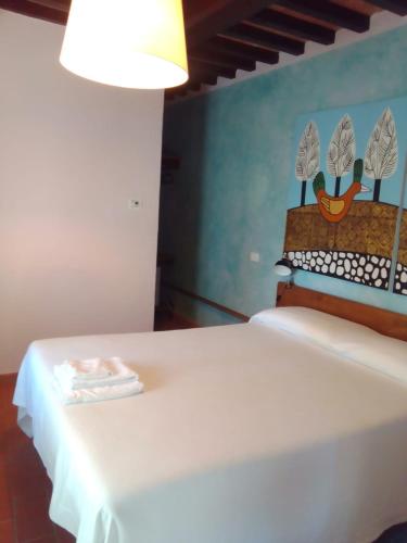 a white bed in a room with a lamp at Sasseta Alta in Scansano