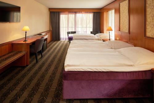 a hotel room with two beds and a desk at Hotel Gladbeck van der Valk in Gladbeck