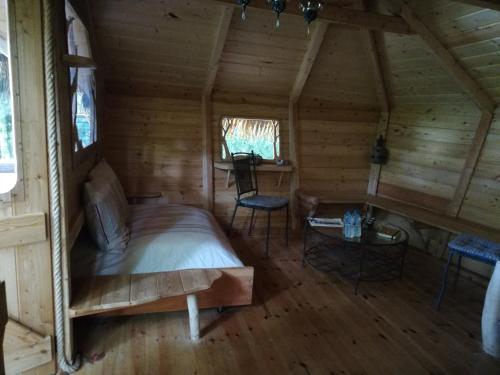 a bedroom in a log cabin with a bed and two chairs at Les hébergements insolites de Quénécan in Perret
