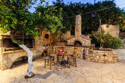 un patio de piedra con mesa y horno de piedra en Petalidi Stone House with garden near the beach, en Petalidi