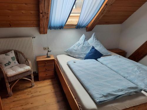 a bedroom with a bed and a chair and a window at Altes Forsthaus in Riedlhütte