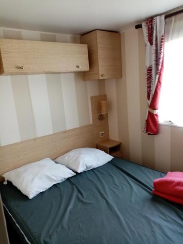 - une chambre avec un lit avec deux oreillers et une fenêtre dans l'établissement location mobile-home IRM super octavia 36m2, à La Tranche-sur-Mer