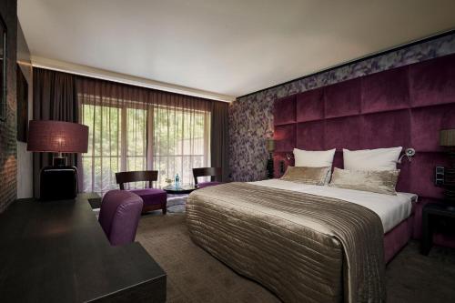 ein Schlafzimmer mit einem großen Bett und einer lila Wand in der Unterkunft Hotel Gladbeck van der Valk in Gladbeck