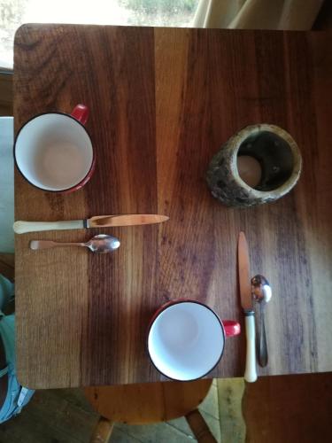 a wooden table with plates and a knife on it at Les hébergements insolites de Quénécan in Perret