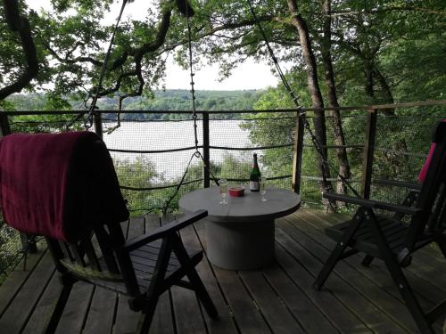 a table and chairs on a deck with a bottle of wine at Les hébergements insolites de Quénécan in Perret