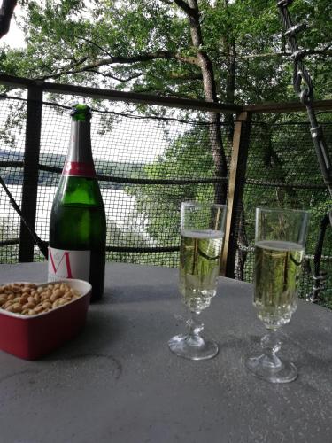 a table with two glasses and a bottle of champagne at Les hébergements insolites de Quénécan in Perret