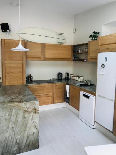 une cuisine avec des armoires en bois et un réfrigérateur blanc dans l'établissement Maison Surf & Nature à Hendaye, à Hendaye