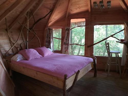 a bed in a room in a wooden cabin at Les hébergements insolites de Quénécan in Perret