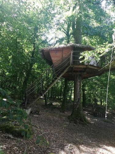 a tree house in the woods with a staircase at Les hébergements insolites de Quénécan in Perret