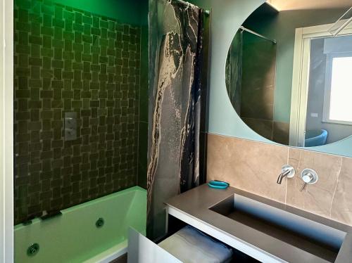 uma casa de banho com um lavatório, uma banheira e um espelho. em OliVia Home Sauna & Gym em Forlì