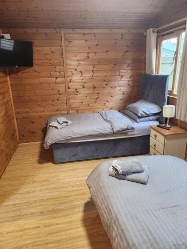 two beds in a room with wooden walls at Southernwood - Family Lodge in Didcot