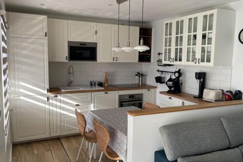 eine Küche mit weißen Schränken und einem Tisch mit Stühlen in der Unterkunft Superbe appartement bord de mer in Saint-Mandrier-sur-Mer