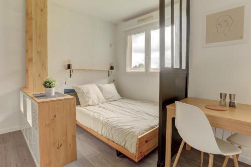 ein kleines Schlafzimmer mit einem Bett und einem Schreibtisch in der Unterkunft Le Sevestre - Plaisir in Plaisir