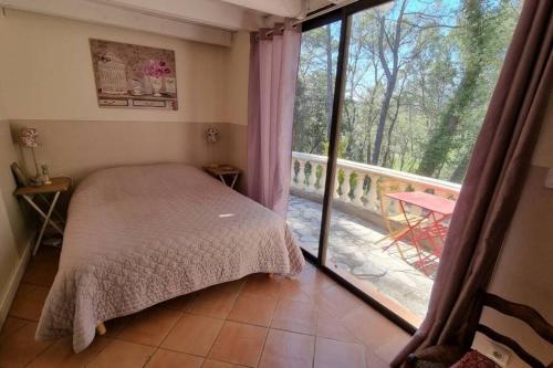 um quarto com uma cama e vista para uma varanda em Maisonnette sur terrain arboré Haut Var em Villecroze