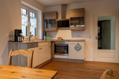 une cuisine avec des placards blancs et une table en bois dans l'établissement Ferienwohnung Vergissmeinnicht Sauerland, à Schmallenberg