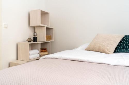 a bedroom with a large white bed with a book shelf at Cozy Studio with private Sauna in Helsinki