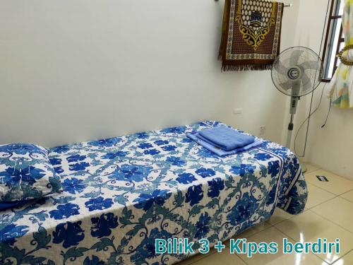 a bedroom with a bed with a blue and white blanket at FJ Homestay in Seri Iskandar