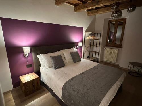 1 dormitorio con 1 cama grande y pared morada en Casa Plauto, en Sarsina