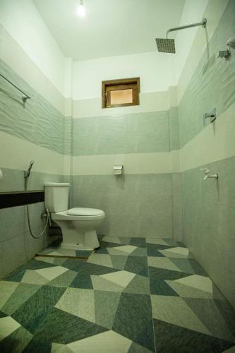 a bathroom with a toilet and a checkered floor at Jim Dandy House in Tissamaharama