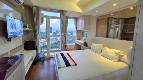a bedroom with a white bed and a large window at Studio18 Elpis Kemayoran JIEXPO Sunrise View -Min Stay 3 nights- in Jakarta