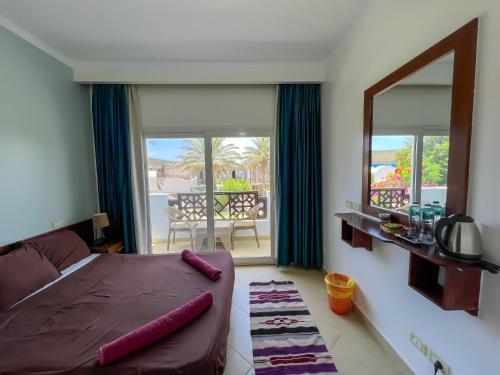 a bedroom with a bed and a mirror and a balcony at Club Red Dahab Motel in Dahab
