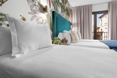 a hotel room with two beds with white pillows at Hotel Los Girasoles by Maxi Hoteles in Granada