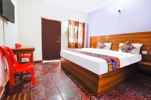 a bedroom with a bed and a red chair at FabHotel Angelo's Inn in Calangute