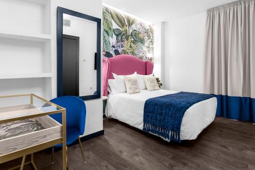 a bedroom with a bed and a blue chair at Hotel Los Girasoles by Maxi Hoteles in Granada