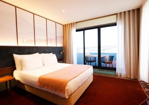 a hotel room with a bed and a large window at Montebelo Viseu Congress Hotel & Spa in Viseu