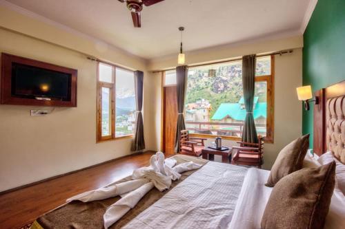 a bedroom with a large bed and a large window at Hotel Grand Oasis in Manāli