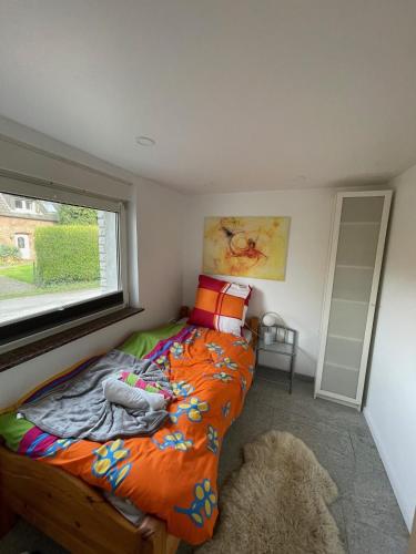 a bedroom with a bed with an orange comforter and a window at Möblierte Wohnung 2 Einzelzimmer in Hünxe