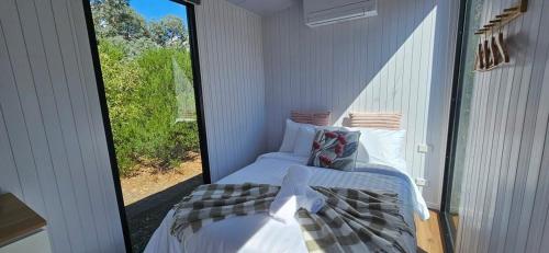 a room with two beds and a large window at Halls Haven Tiny House 2 in Halls Gap