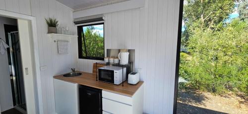 eine Küche mit einer Theke mit einer Mikrowelle und einem Fenster in der Unterkunft Halls Haven Tiny House 2 in Halls Gap