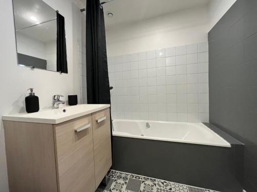 een badkamer met een bad, een wastafel en een bad bij Beau F2 rénové au coeur de Caen in Caen