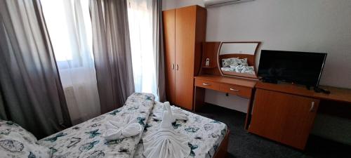 a hotel room with a bed and a desk with a television at Hotel Pescarus Port Bicaz in Bicaz