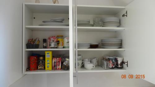 a white pantry with plates and dishes on shelves at Apartament Slupsk in Słupsk