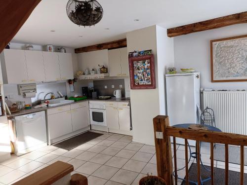 uma cozinha com armários brancos e electrodomésticos brancos em maison immersion hautes alpes em Freissinieres
