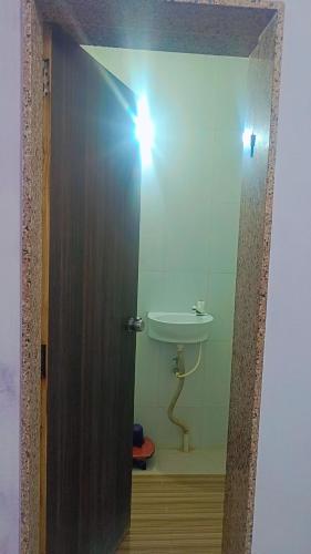 uma porta para uma casa de banho com um lavatório e uma luz em shree swaminarayan vishranti bhawan em Dwarka