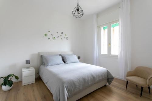 a white bedroom with a bed and a chair at Dandolo apartment by Welc(h)ome in Treviso