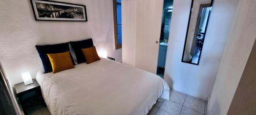 - une chambre dotée d'un lit blanc avec des oreillers jaunes et noirs dans l'établissement LE MONTMORENCY 35 Authentique Centre Historique Climatisation, à Sète