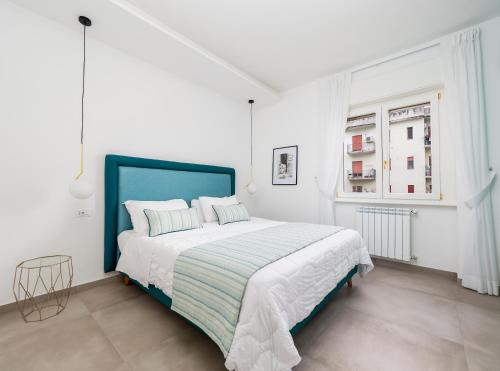 um quarto branco com uma cama grande e uma janela em Amal - Elegant apt in Sorrento em Sorrento