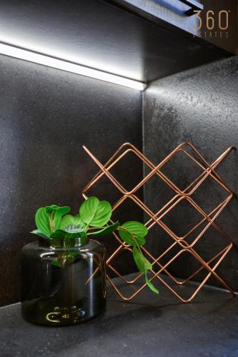 a black vase with a plant in front of a wall at Stunning 3BR Townhouse with Private Rooftop Access by 360 Estates in Paola