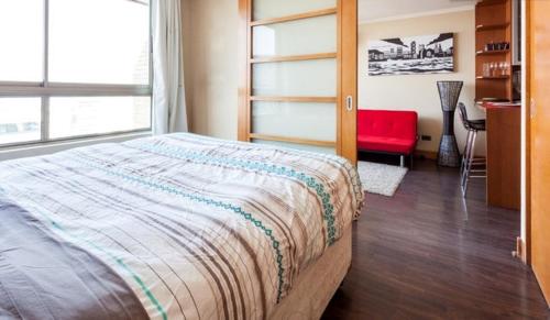 sypialnia z dużym łóżkiem i czerwonym krzesłem w obiekcie Departamento en Centro Providencia w mieście Santiago