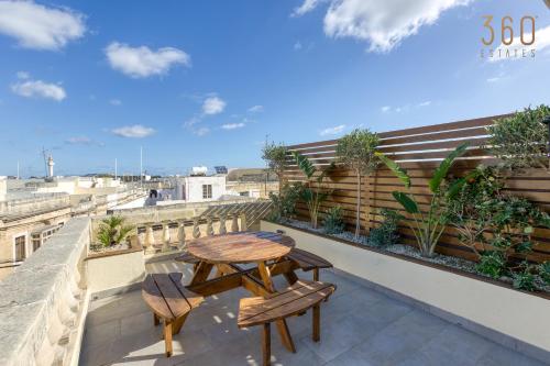 y balcón con mesa y sillas de madera. en Stunning 3BR Townhouse with Private Rooftop Access by 360 Estates, en Paola