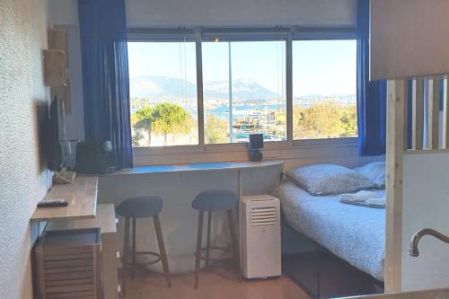 1 dormitorio con 1 cama y escritorio con 2 taburetes en Vue Mer sur l'isthme plage à 2 min. Arrivée H24, en La Seyne-sur-Mer